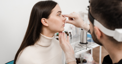 A woman's nose is inspected by a medical professional.