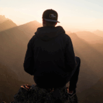 individual's silhouette as they face a mountain range, letting go of the past and forgiving themselves in recovery